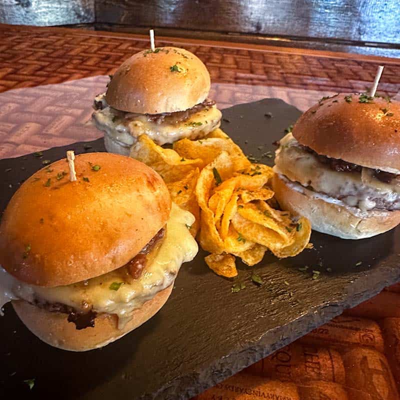 Three Wagyu beef sliders sliders with bacon onion jam, cheese, pickles, and kettle chips